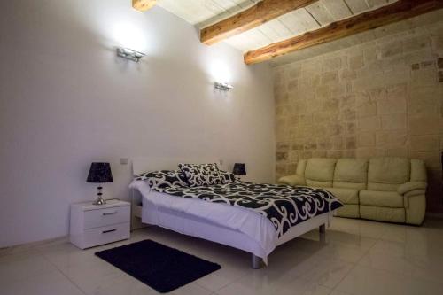 a bedroom with a bed and a couch at Valletta-Central duplex maisonette in Valletta