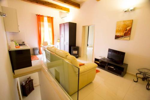 a living room with a yellow couch and a television at Valletta-Central duplex maisonette in Valletta