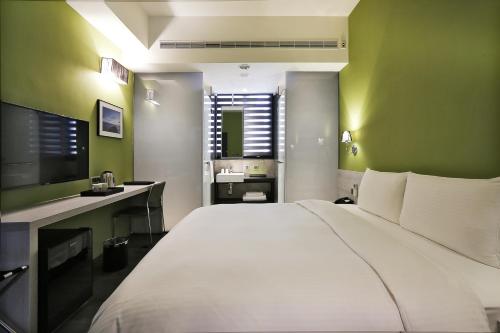 a bedroom with a large white bed and green walls at Miller Inn in Taichung