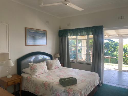 a bedroom with a bed and a large window at BillsBest Greengates Cottages in Port Edward