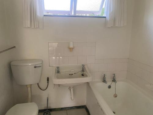 a bathroom with a toilet and a sink and a tub at BillsBest Greengates Cottages in Port Edward