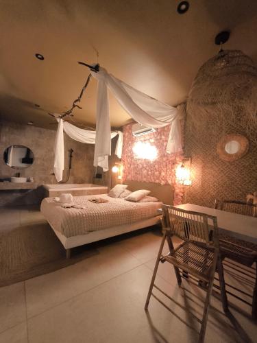 a bedroom with a bed and a table and a chair at L'expérience LOVE ROOM in Saint-Jean-Bonnefonds