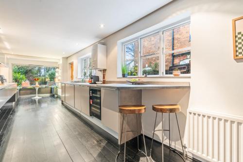 a kitchen with a counter and two stools at Elegant 5-Bed House Free Parking Edgbaston, Birmingham in Birmingham