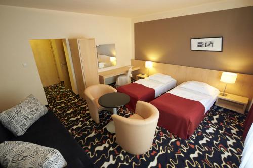 a hotel room with two beds and a couch at Hotel Laterum in Pécs