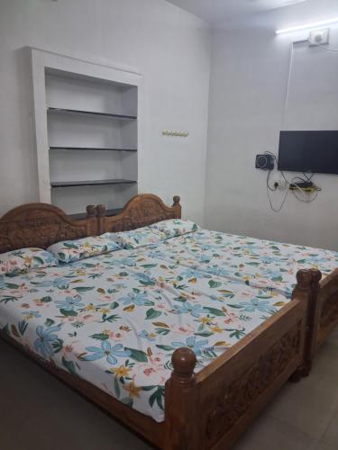 a bedroom with a bed with a floral comforter at Bhavadesh Lodge in Virudunagar