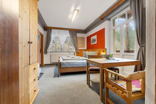 a bedroom with a bed and a desk and a table at Pension Schrammsteinbaude in Bad Schandau