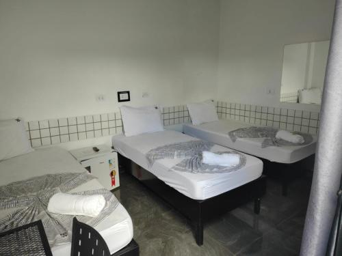 a group of three beds in a room at Hotel XV in Piracicaba