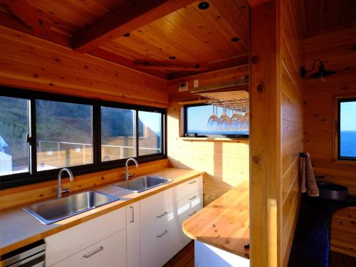 a kitchen with two sinks and windows in a cabin at On The Cliff in Karatsu
