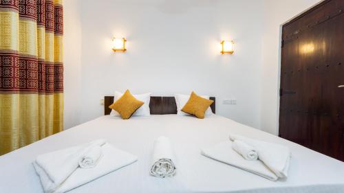 a bedroom with a white bed with two towels at Pearl Guest House in Dambulla