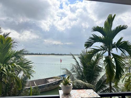 a view of a body of water with palm trees and a boat at Autumn Bay Retreat in Hoi An