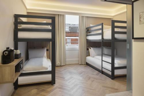 two bunk beds in a room with a window at The Drey - Kensington, Earl's Court in London