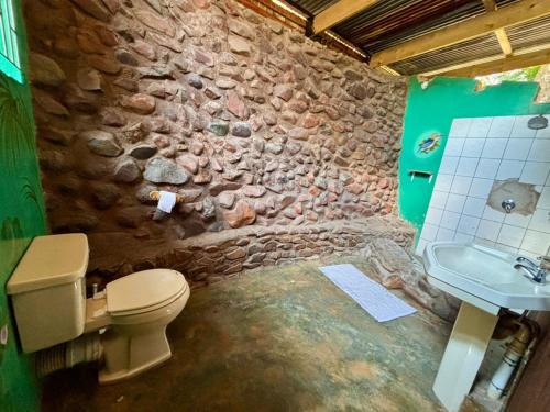 a stone bathroom with a toilet and a sink at Backpackers at Kanaan in Hazyview
