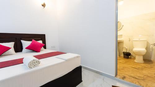 a bedroom with a bed with red and white pillows at Pearl Guest House in Dambulla