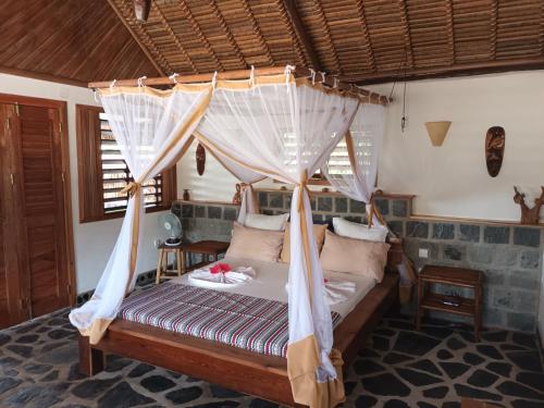 a bedroom with a bed with a canopy at Ravoravo Beachfront Family lodge in Lokobe National Park-Nosy be, autentic Madagascar expiriance with europian confort in Antafondro