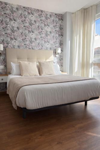 a bedroom with a large bed with a floral wall at Hotel Villa del Son in Porto do Son