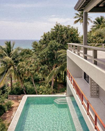 a house with a swimming pool next to the ocean at W15 Hiriketiya in Dickwella