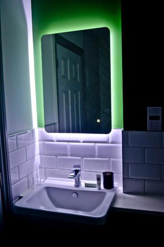 a bathroom with a sink with a green light at The Ugly Duckling in Telford