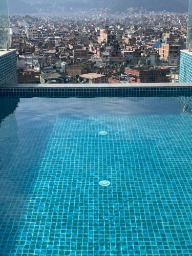 a large swimming pool with a city in the background at Ambassador Garden Home in Kathmandu