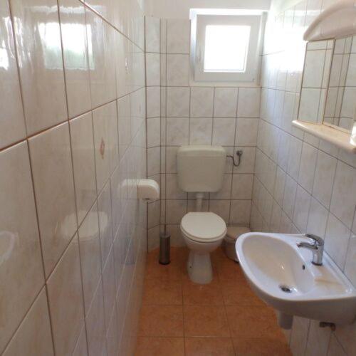 a white bathroom with a toilet and a sink at Apartments Villa Jagoda in Rab