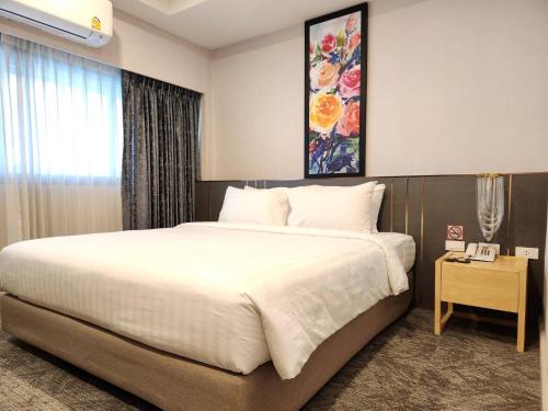 a bedroom with a large white bed and a window at โรงแรมสวนดุสิต เพลส in Ban Nong Chaeng