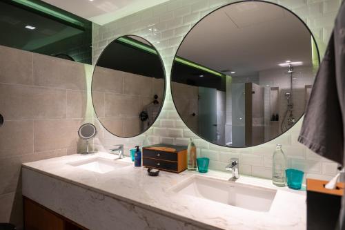 a bathroom with two sinks and two mirrors at Cross Chiang Mai Riverside in Chiang Mai