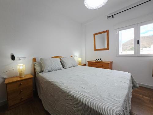 a bedroom with a white bed and a window at La Artesana Níjar in Níjar