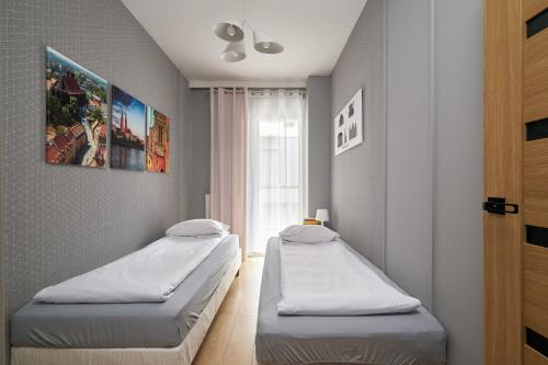 two twin beds in a room with a window at Apartamenty City Tower od WroclawApartament-pl in Wrocław