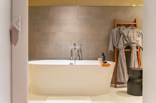 a bath tub in a bathroom with a robe at Cross Chiang Mai Riverside in Chiang Mai