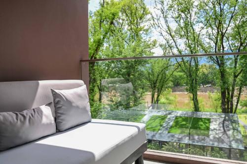 a white couch sitting in front of a large window at Cross Chiang Mai Riverside in Chiang Mai