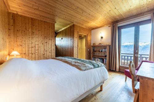 a bedroom with a bed and a large window at Chalet Sapi in Combloux