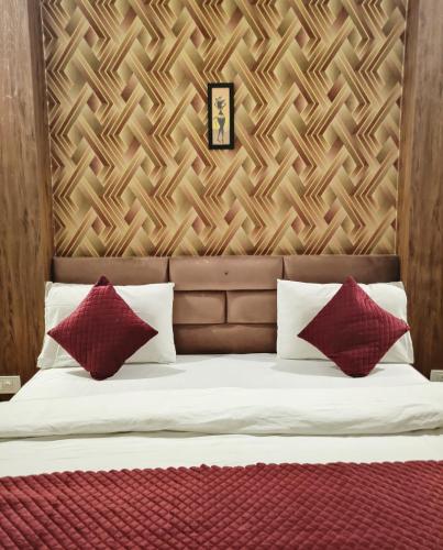 a bed with two red pillows and a wooden wall at Hotel Padma Residency in Datia