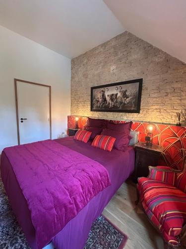 a bedroom with a large purple bed and a couch at Le Chêne Guesthouse in Aunou-sur-Orne