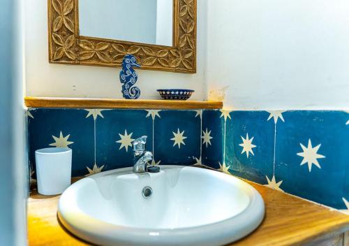 a bathroom with a white sink and a mirror at Dhow House - Rooftop Lounge with Sunrise Views in Bagamoyo