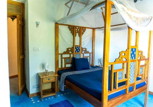 a bedroom with a canopy bed with blue sheets at Dhow House - Rooftop Lounge with Sunrise Views in Bagamoyo