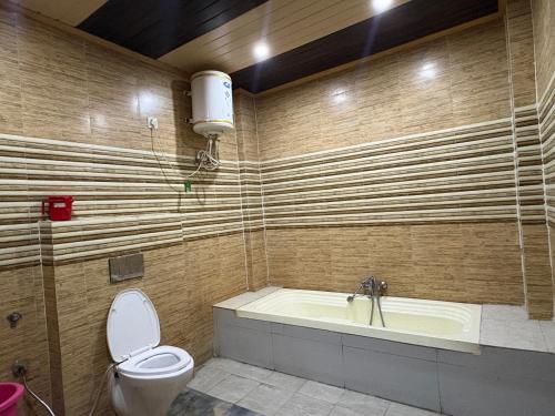 a bathroom with a tub and a toilet and a sink at Hotel Shyam Regency in Sabāthu