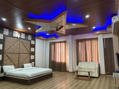 a bedroom with a bed and a chair and blue lights at Hotel Shyam Regency in Sabāthu