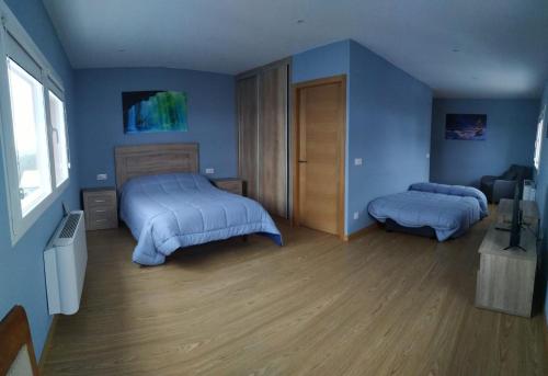 a bedroom with two beds and blue walls at Pensión Palomos in San Xoán de Río
