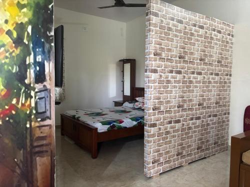 a bedroom with a bed and a brick wall at Sreevara Farms in Hosūr