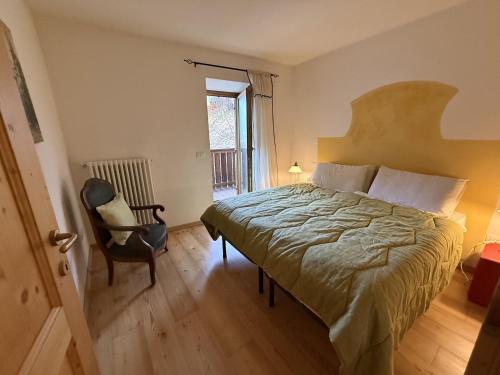 a bedroom with a bed and a chair and a window at Il Molino nel bosco - PT in Alleghe