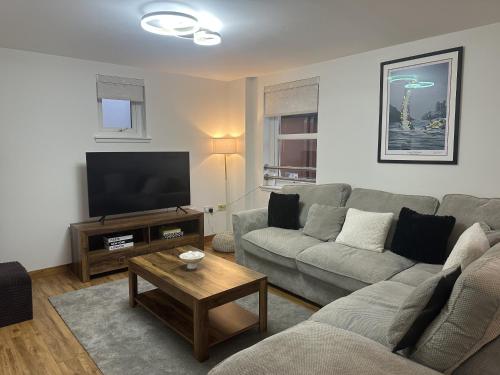 a living room with a couch and a flat screen tv at LaScala Apartment in Inverness