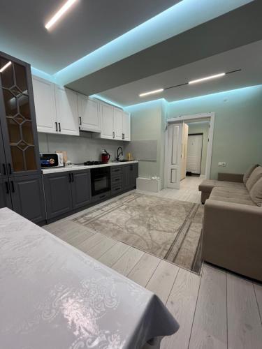 una cucina con mobili bianchi e un divano in una stanza di Nomad Home a Bishkek