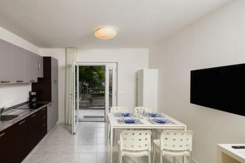 a kitchen with a table with chairs and a television at Appartamenti Villa al Fiume in Nago-Torbole