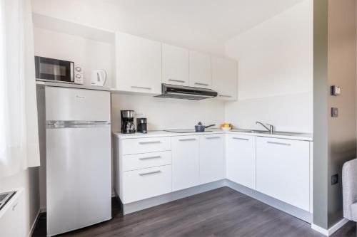a white kitchen with white cabinets and appliances at Appartamenti Villa al Fiume in Nago-Torbole