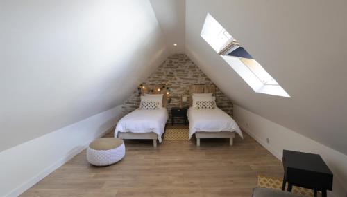 a attic room with two beds and a window at Gite Kalon in Pouldreuzic
