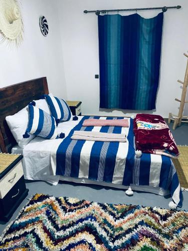 a bed with a blue and white blanket and a rug at calm stay ouassane in Essaouira