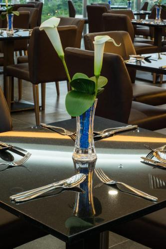 a glass vase with a flower on a table at Hotel Labuan Point in Labuan