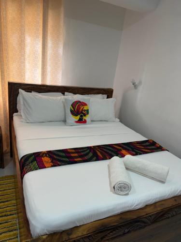 a bedroom with a large bed with white sheets and towels at Charming chalet Diani in Diani Beach