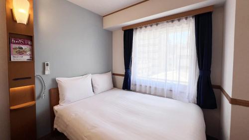 a small bedroom with a bed and a window at Toyoko Inn Hakata Nishi-nakasu in Fukuoka