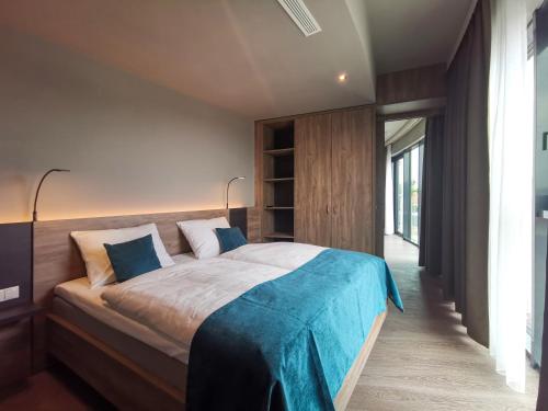 a bedroom with a large bed with a blue blanket at H24 Stadthotel Bernau in Bernau bei Berlin