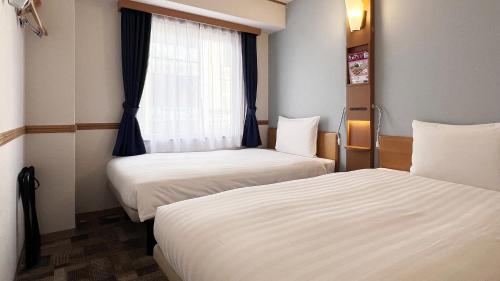 a hotel room with two beds and a window at Toyoko Inn Hakata Nishi-nakasu in Fukuoka